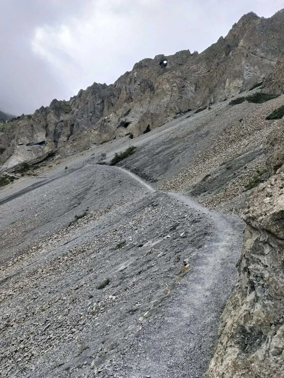 A narrow rocky trekking trail carved into a steep mountain slope during the Annapurna Circuit trek