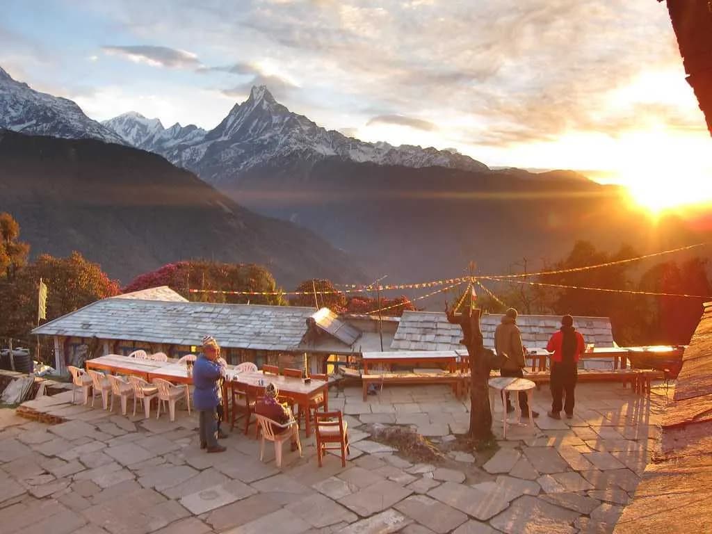 Trekkers on a stone terrace watching the sun set over the iconic Machhapuchhre peak during the Ghorepani Ghandruk trek