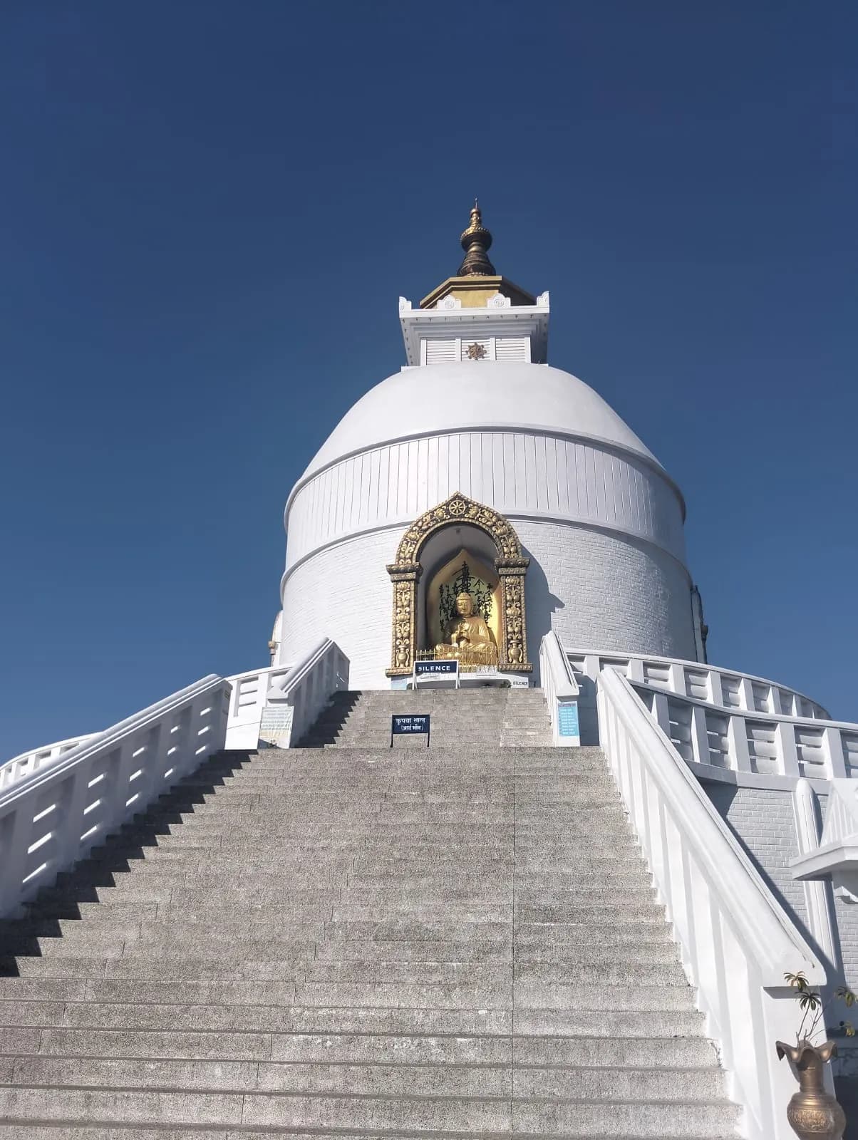 The gleaming white Shanti Stupa in Pokhara with steep stone steps leading up to a golden Buddha statue