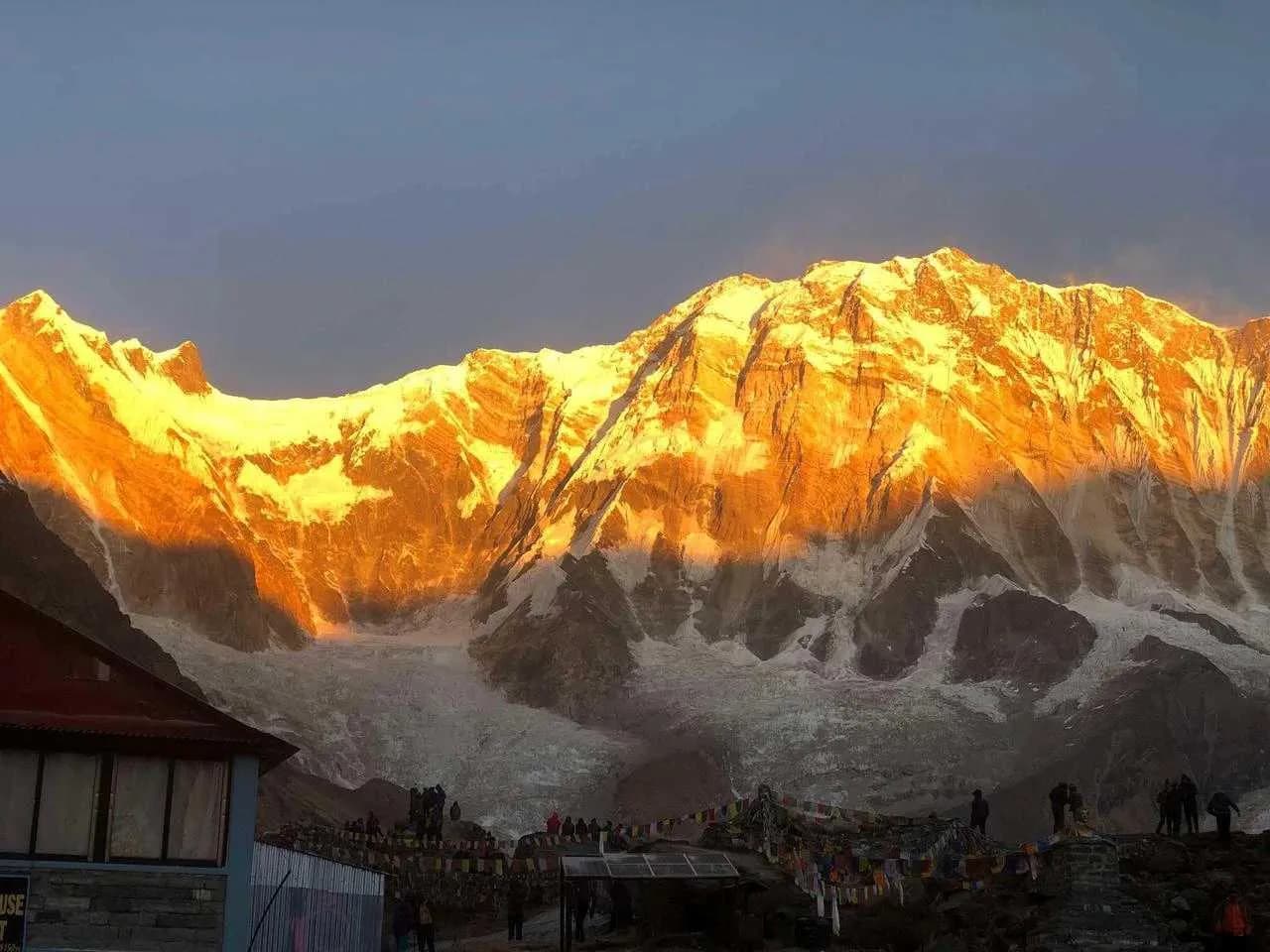 Golden sunrise over Annapurna peaks with trekkers gathered at Annapurna Base Camp viewpoint
